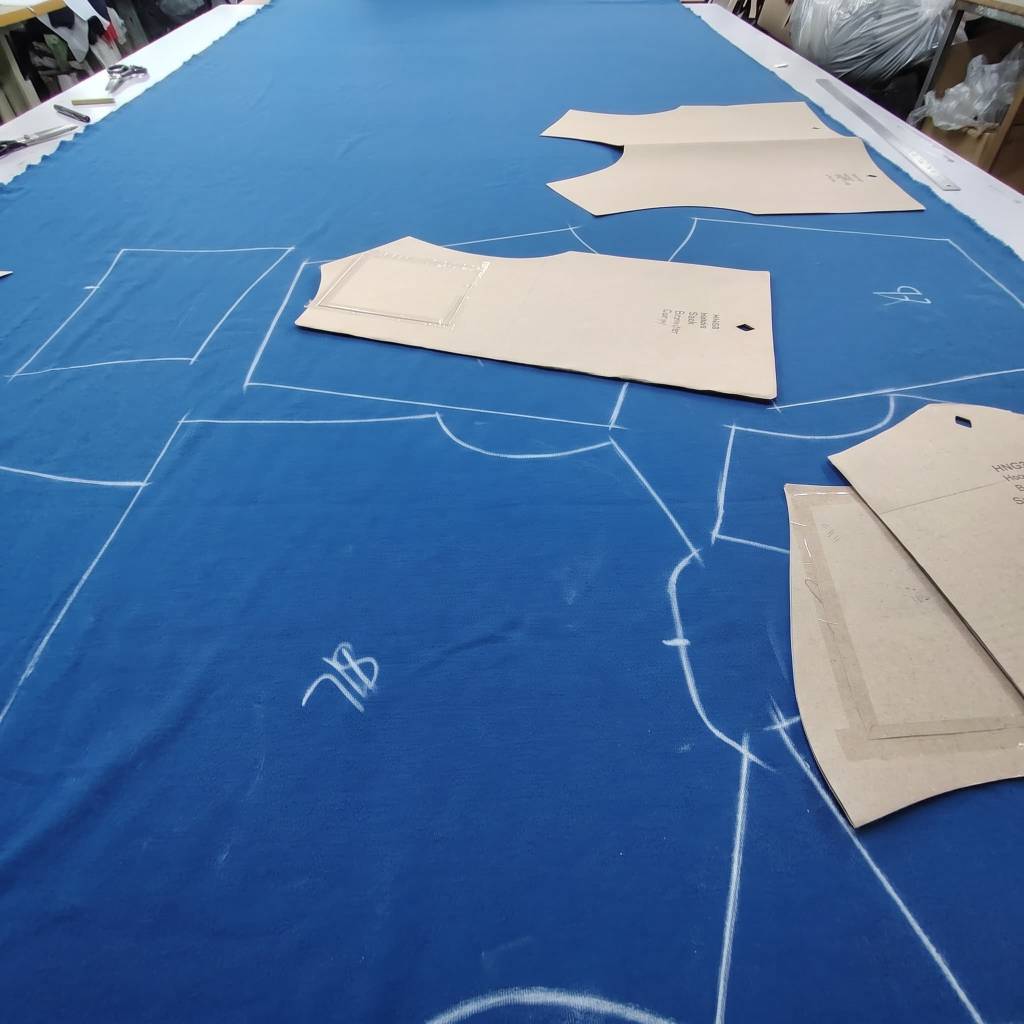 Pattern drafting with chalk outlines and templates on royal blue fabric
