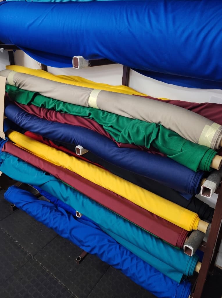Colourful school uniform fabric rolls stored on the workshop rack