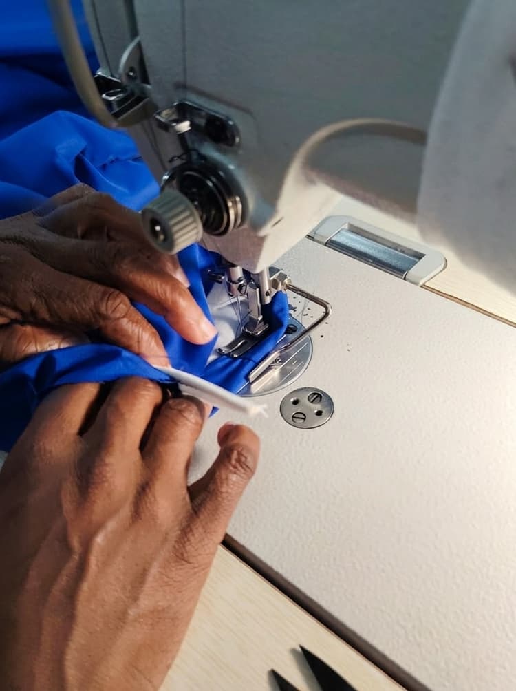 Skilled hands guiding uniform fabric under industrial sewing machine