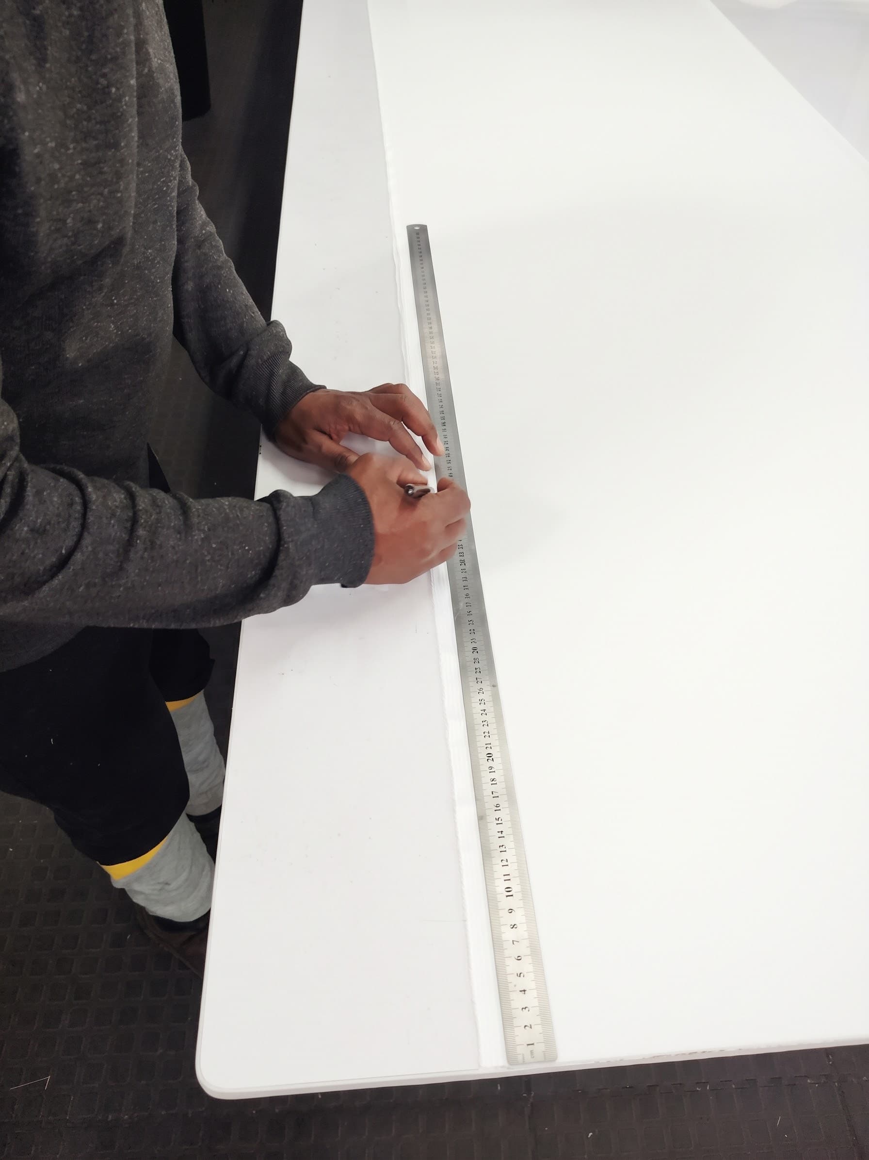 Craftsman using precision steel ruler to measure and cut pattern fabric in the workshop